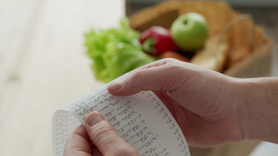 Person reviews receipt over grocery items on counter